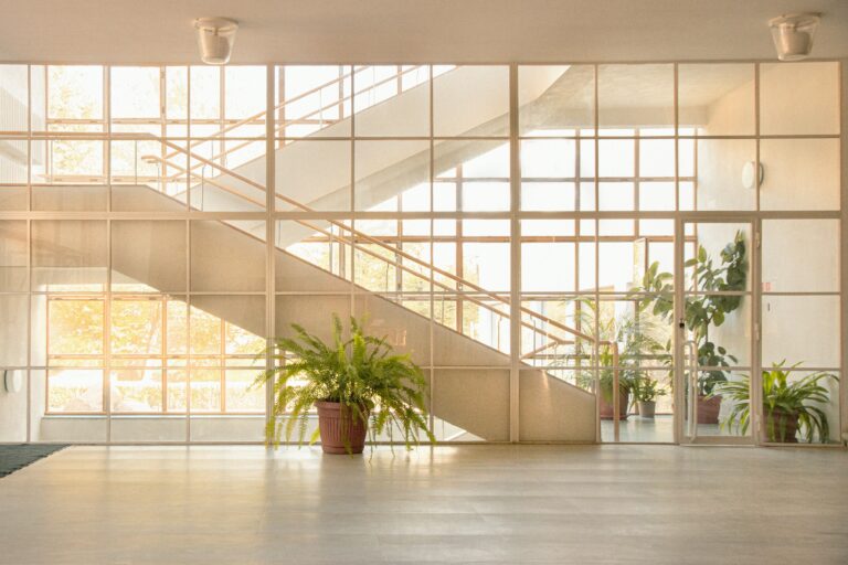 A large lobby with bright green plants and floor-to-ceiling windows